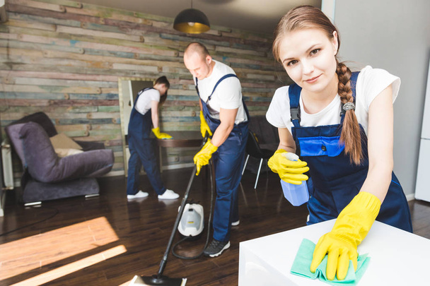 Cleaning service with professional equipment during work. professional kitchenette cleaning, sofa dry cleaning, window and floor washing. man and women in uniform, overalls and rubber gloves - Photo, Image