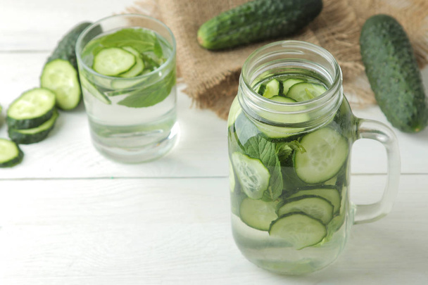 water with cucumber. Refreshing diet water with cucumber in a glass cup on a light background. detox drink concept. summer refreshing drink. - Foto, Bild