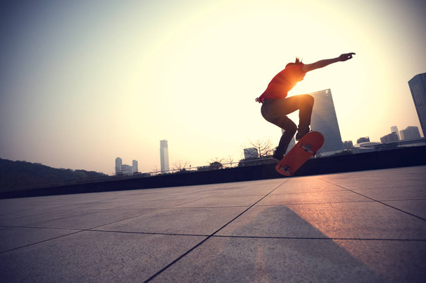 Skateboarder skateboarding at sunrise in urban city - Фото, изображение