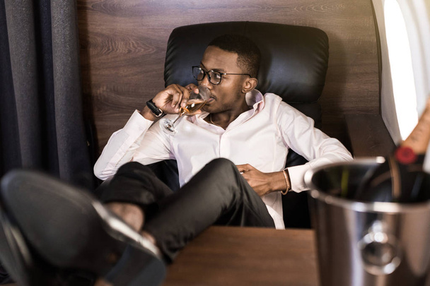Successo giovane afro americano nero uomo d'affari seduto sulla sedia del suo jet privato
 - Foto, immagini