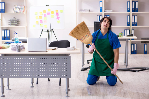 Мужчина красивый профессиональный уборщик работает в офисе  - Фото, изображение