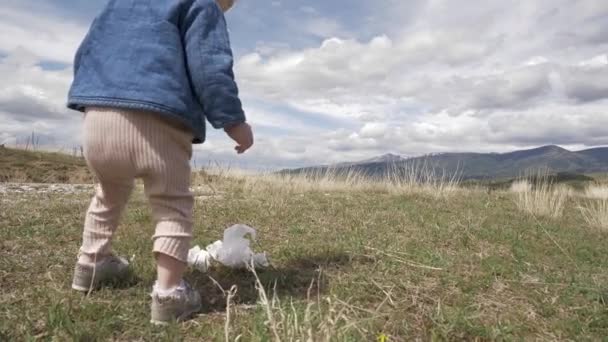 Klein blond meisje dat afval in de natuur verzamelt, de maatschappij tegen vervuiling - Video