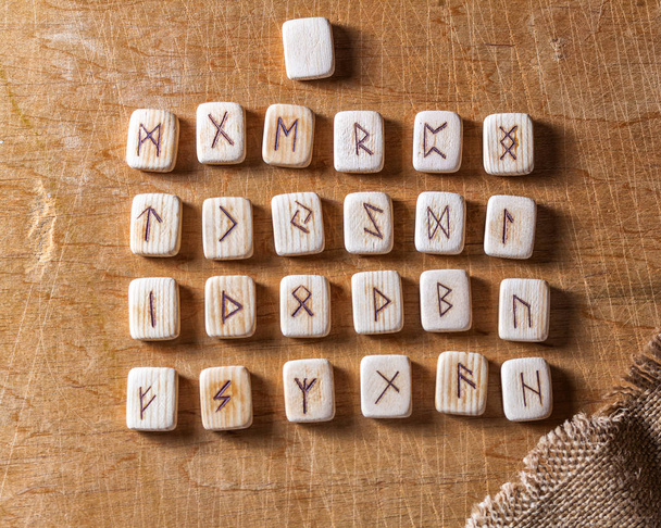 Runas hechas a mano de madera anglosajona en la mesa vintage En cada símbolo de runa para la adivinación se designa
 - Foto, Imagen