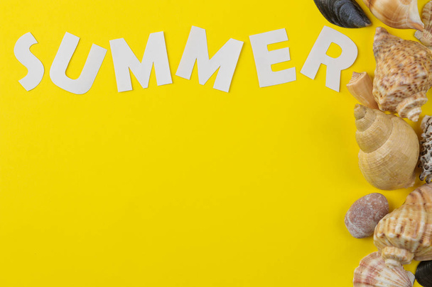 Na jasně žlutém pozadí je nápis v létě s bílými písmeny a mušle. Letní. Relaxační. Dovolenou. pohled shora - Fotografie, Obrázek