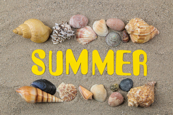 Inscrição verão de papel letras amarelas e conchas na areia do mar. Verão. relaxamento. De férias. vista superior
 - Foto, Imagem
