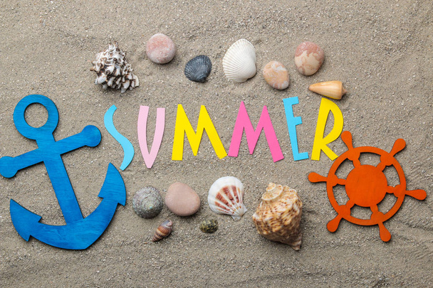 Inscripción de verano de papel de letras multicolores y conchas marinas y accesorios de verano en la arena del mar. Verano. Relajación. vacaciones. vista superior
 - Foto, imagen