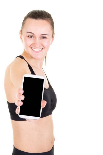 Портрет усміхненої молодої стрункої спортивної жінки, що вказує смартфон
 - Фото, зображення