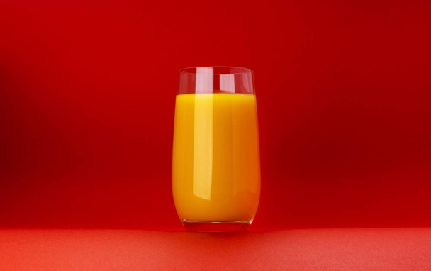 Glass of orange juice isolated on red background with copy space - Photo, Image