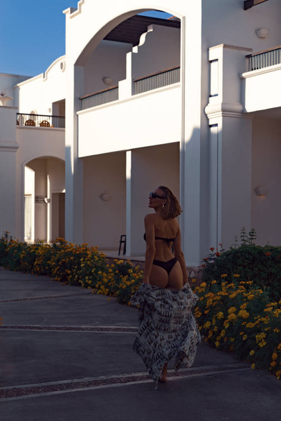 stylish girl walks in a bathing suit in the garden at the hotel - Fotografie, Obrázek