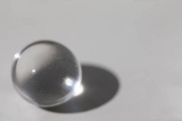 Стеклянный шар на сером фоне с тенью
 - Фото, изображение