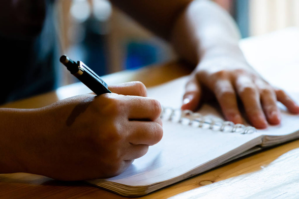 Kobieta ręka z ołówkiem pisanie na notebooku w kawiarni. Kobieta - Zdjęcie, obraz