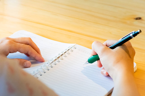 Kobieta ręka z ołówkiem pisanie na notebooku w kawiarni. Kobieta - Zdjęcie, obraz