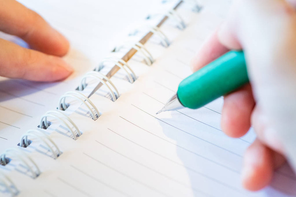 θηλυκό χέρι με μολύβι γράφοντας στο σημειωματάριο στην καφετέρια. - Φωτογραφία, εικόνα