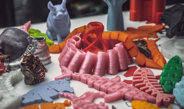 Mnoho pestrobarevných objektů vytištěných na 3D tiskárně leží na plochém povrchu - Fotografie, Obrázek