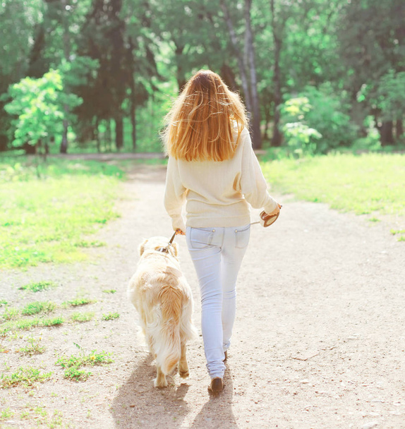 back view owner woman and Golden Retriever dog walking in spring - Фото, изображение