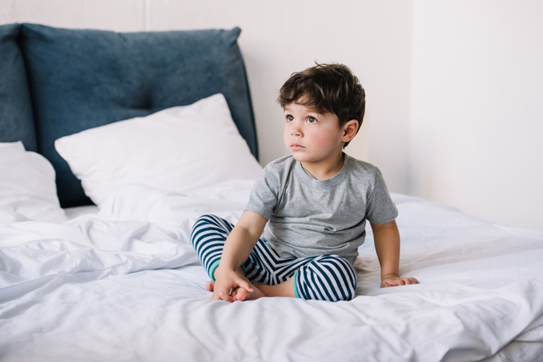 cute kid with barefoot sitting on bed at home  - Foto, afbeelding