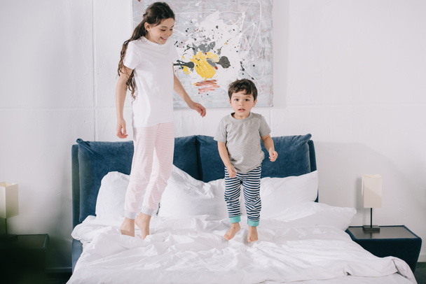happy child jumping on bed with adorable toddler brother  - Foto, imagen
