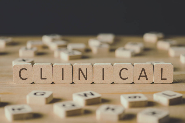 selective focus of clinical lettering on cubes surrounded by blocks with letters on wooden surface isolated on black - Photo, Image