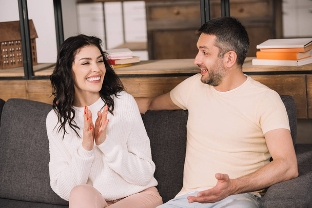 happy man looking at cheerful brunette woman clapping hands at home  - Photo, Image