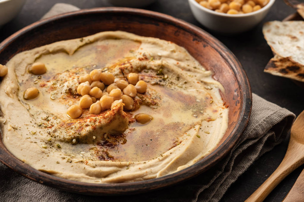 Hummus clásico con garbanzos, pimentón, aceite de oliva y especias orientales. Snack popular mediterráneo de garbanzos y pasta tahini
. - Foto, Imagen