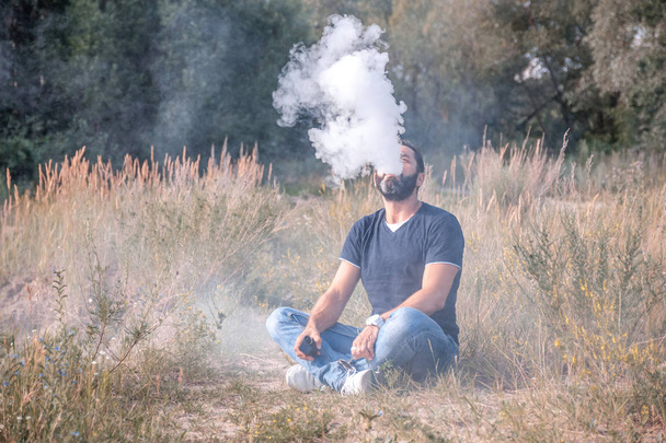 Fumador elegante vapeo y libera una nube de vapor. Deshacerse de la adicción a la nicotina
. - Foto, Imagen