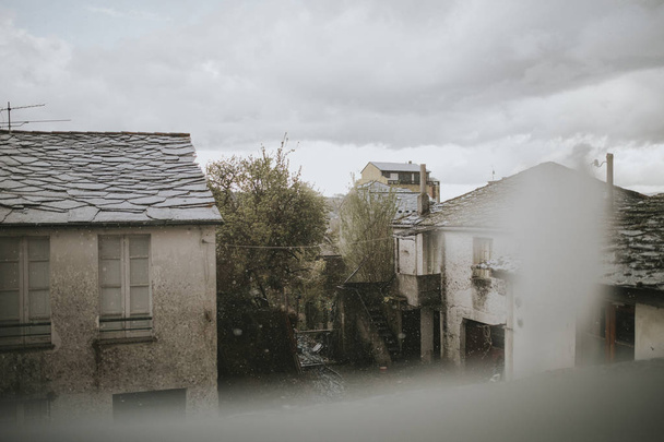 Galician village viewed from a window in a rainy day with grey clouds in the sky - Foto, imagen