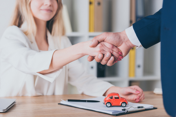 partial view of smiling woman shaking hands with car dealer in office - Photo, Image