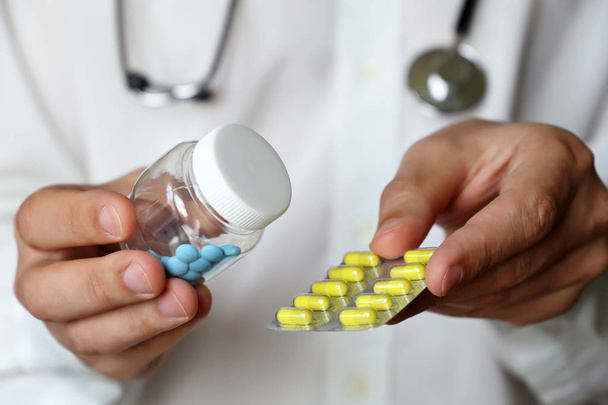 Orvos, üveg tablettát, és buborékfólia csomag kapszula, amely gyógyszert ad. Az orvosi rendelvény fogalma, kábítószerek, vitaminok, gyógyszertár, a kezelés megválasztása - Fotó, kép