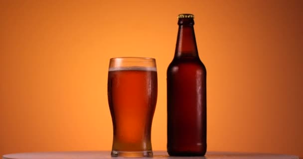 Butelka i szklanka piwa obracające się w zwolnionym tempie. Widok z bliska, strzał na czerwonym aparacie 6k - Materiał filmowy, wideo
