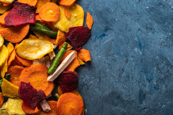 Verduras fritas secas de zanahoria, remolacha, chirivía y otras verduras en fondos azules. Dieta orgánica y comida vegana
. - Foto, Imagen
