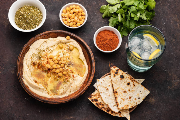 Hummus clásico con garbanzos, pimentón, aceite de oliva y especias orientales. Snack popular mediterráneo de garbanzos y pasta tahini
. - Foto, Imagen