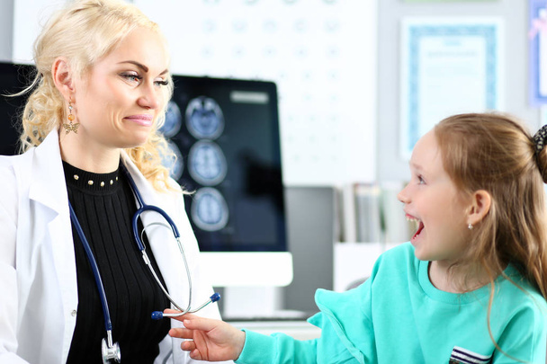Enthusiastic cute little patient laughing at doctor office during tests - Photo, Image