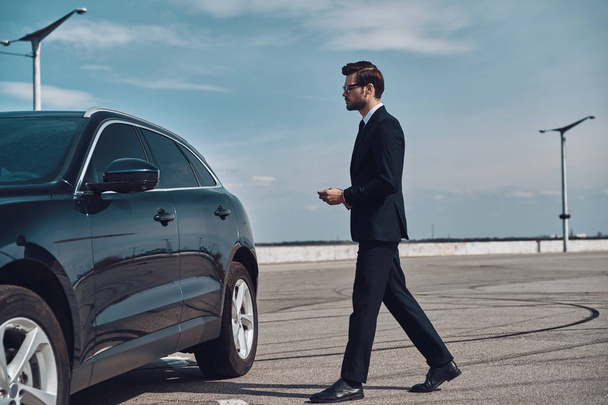 Modern businessman. Full length of handsome young businessman walking to his car  - Photo, image