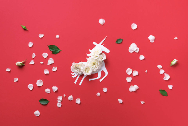 Creative layout. White unicorn with flowers over coral paper background. Invitation or holiday card for birthday. Summer concept. Top view - 写真・画像