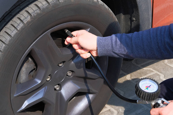 Automobile maintenance concept. Car service. Male hand checks pressure in car tires. - Photo, Image