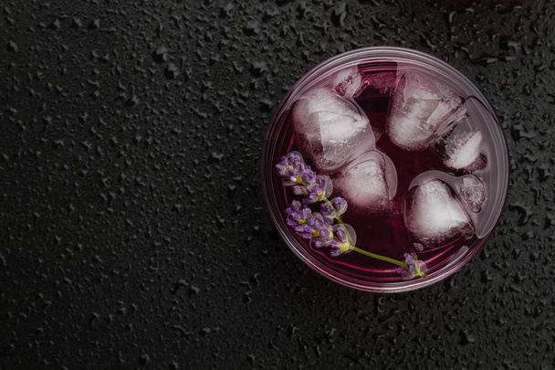 Lavender lemonade with ice on wet black background. - Zdjęcie, obraz