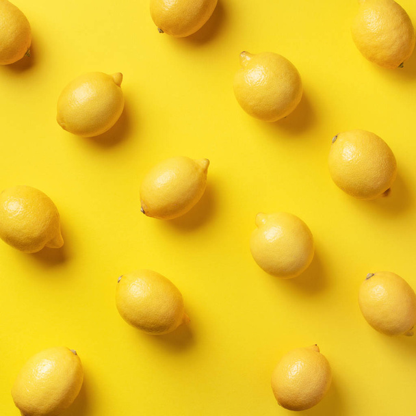 Food pattern with lemons on yellow paper background. Top view. Summer concept. Vegan and vegetarian diet. Square crop - 写真・画像