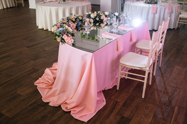 vista de ángulo alto de la mesa con mantel rosa, vasos vacíos y decoraciones florales en la recepción de la boda
  - Foto, imagen
