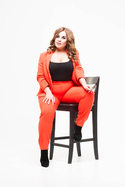 Plus size model with big breast and deep decollete, fat woman on white background in orange pantsuit, body positive concept - Foto, Bild
