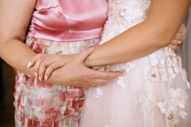 ritagliato colpo di sposa in abito da sposa abbracciando con la donna in abito rosa
 - Foto, immagini