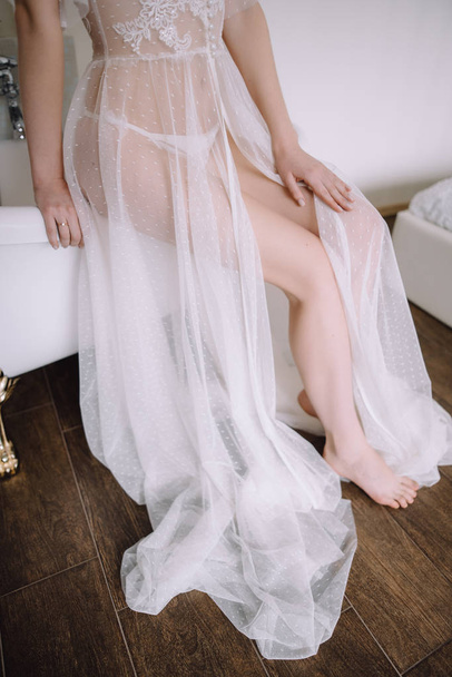 cropped shot of young bride in white dress sitting on bathtub  - 写真・画像