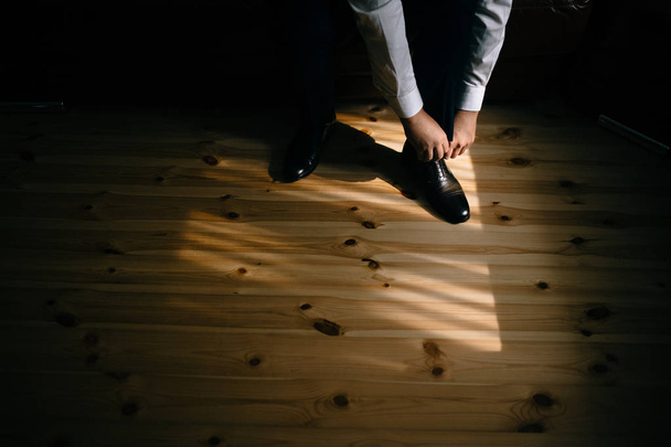 low section of groom wearing shoes in the morning, high angle view - Photo, Image