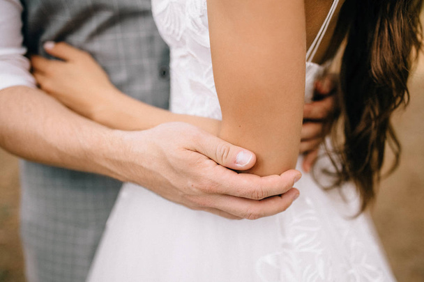 close-up partial view of young wedding couple hugging outdoor - Photo, image