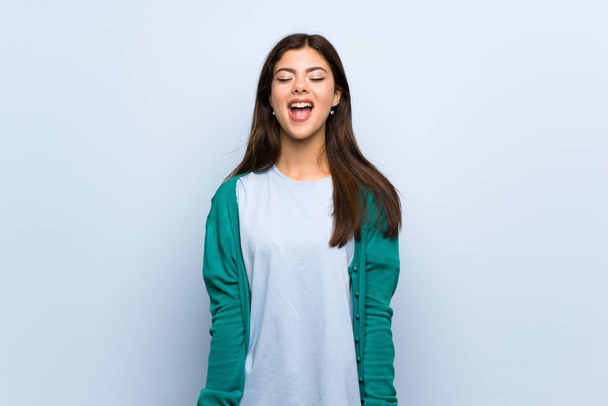 Adolescente menina sobre a parede azul gritando para a frente com a boca aberta
 - Foto, Imagem