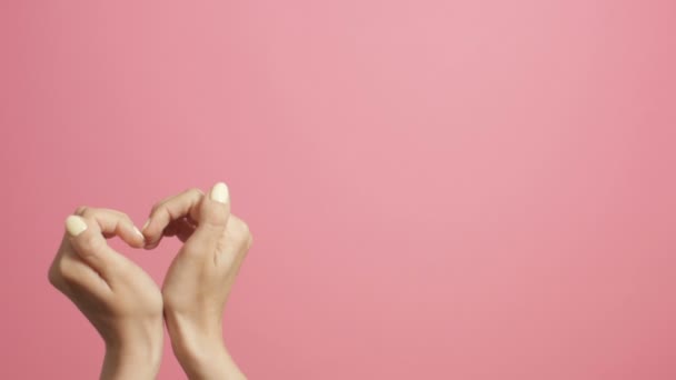 Frauen herzförmige Hände, kreative Liebeserklärung, Live-Postkarte, Herzschläge auf rosa Studiohintergrund - Filmmaterial, Video