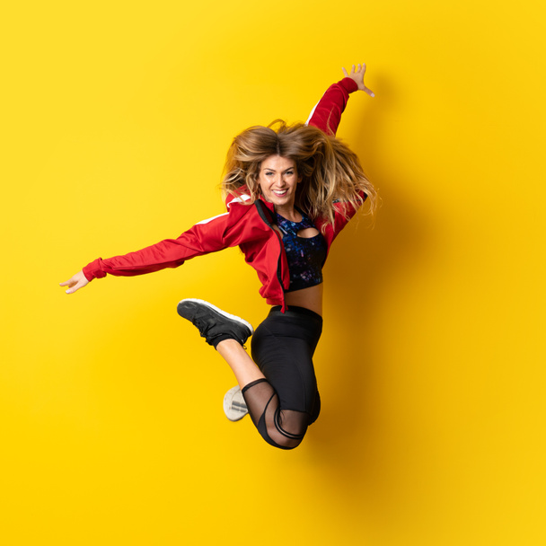 Urban Ballerina dancing over isolated yellow background and jumping - Fotografie, Obrázek