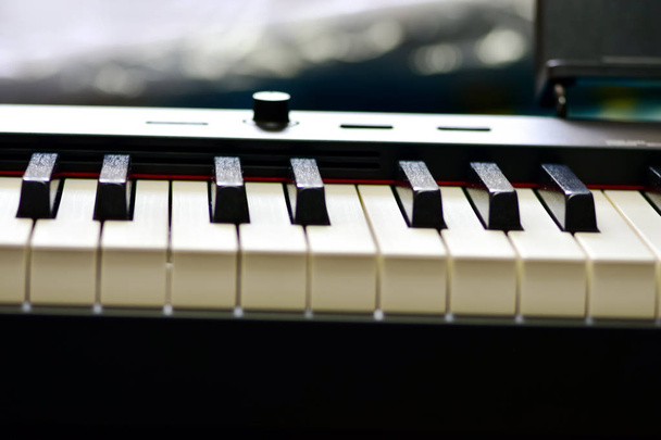 Toetsen van een digitale piano, zachte scherpstelling, creatieve sfeer van een persoon improvisatie en creativiteit. MIDI piano keyboard voor het afspelen van digitale muziek en het maken van remixes. - Foto, afbeelding