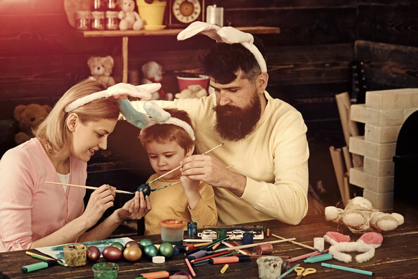 Easter bunny costume. Mother, father and child painting Easter eggs. - Photo, image