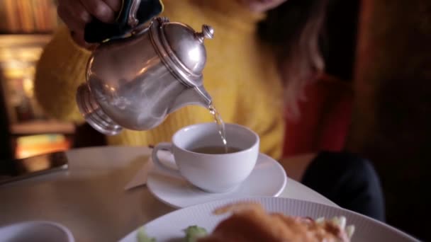 young pretty woman in yellow sweater having breakfast in cozy cafe and drinking tea - Footage, Video