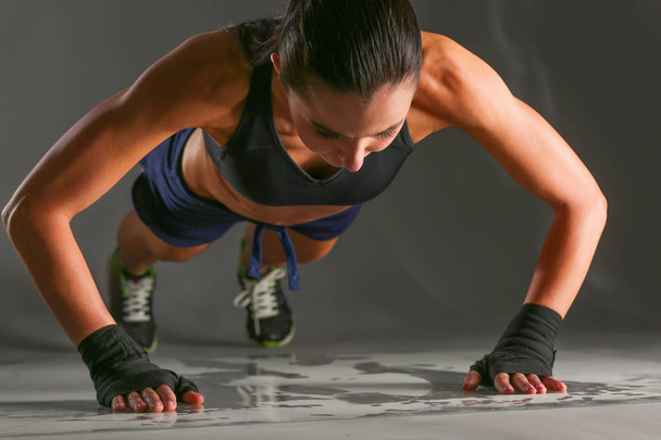 Young woman doing push ups on a mat. - Valokuva, kuva